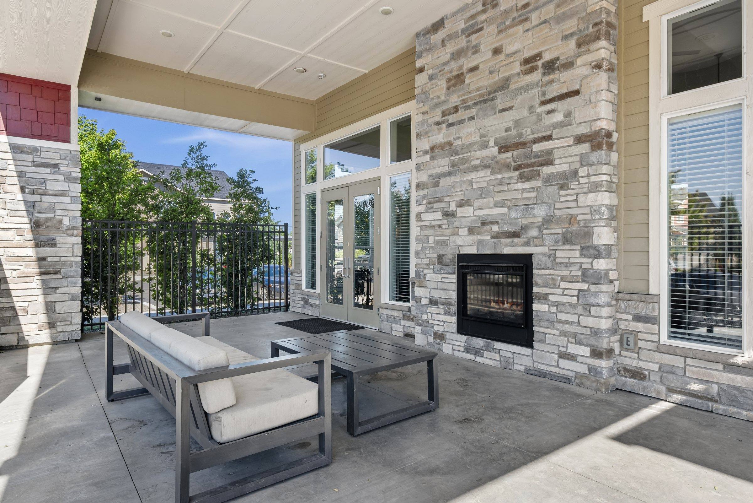 The covered outdoor lounge with a stone fireplace and patio seating