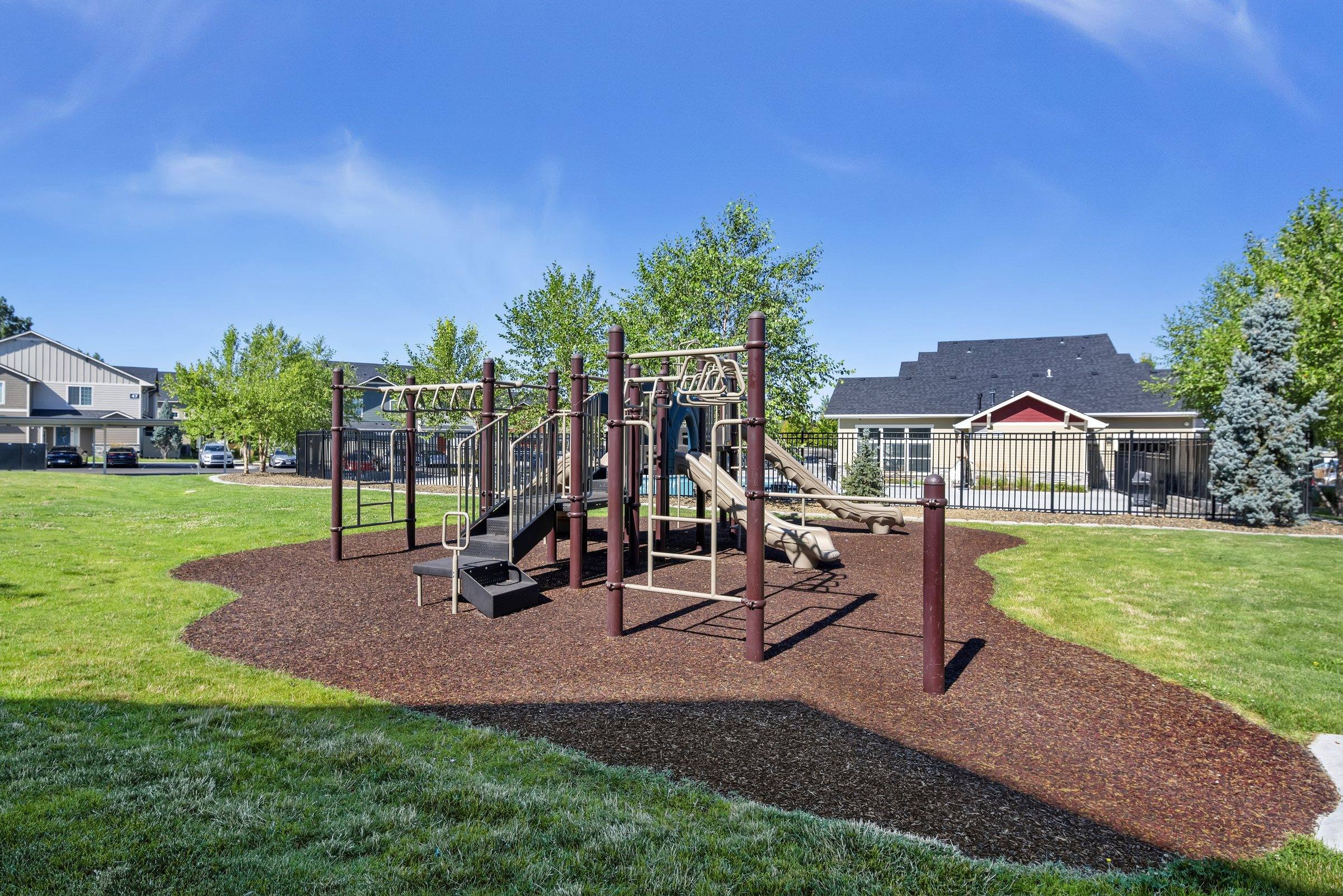The on-site playground with climbing equipment on a landscaped lawn