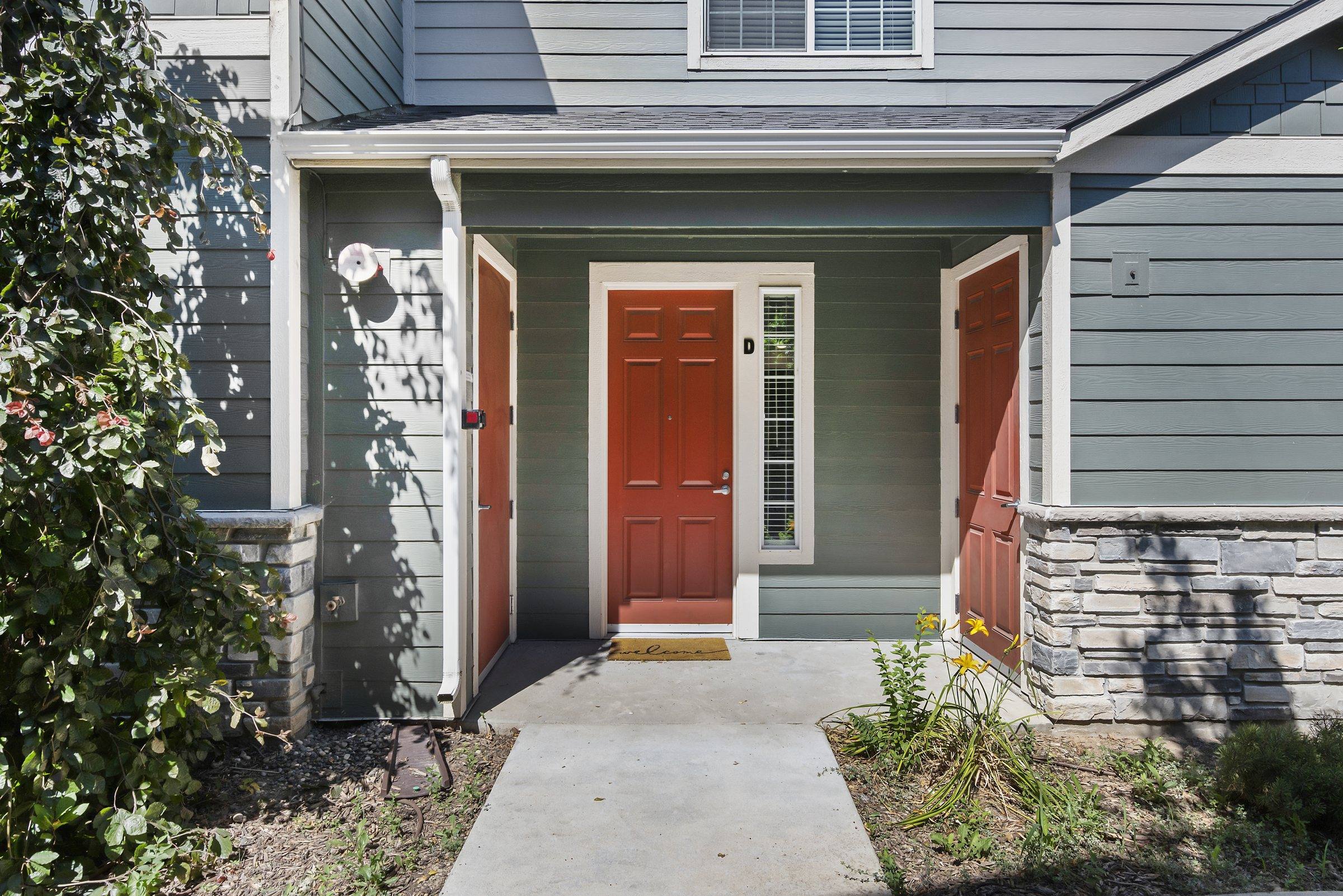 A private townhome entry with a covered porch and stone accents