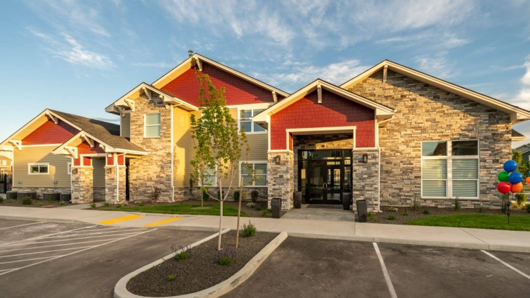The Enclave clubhouse entrance with a stone and timber facade under a clear sky