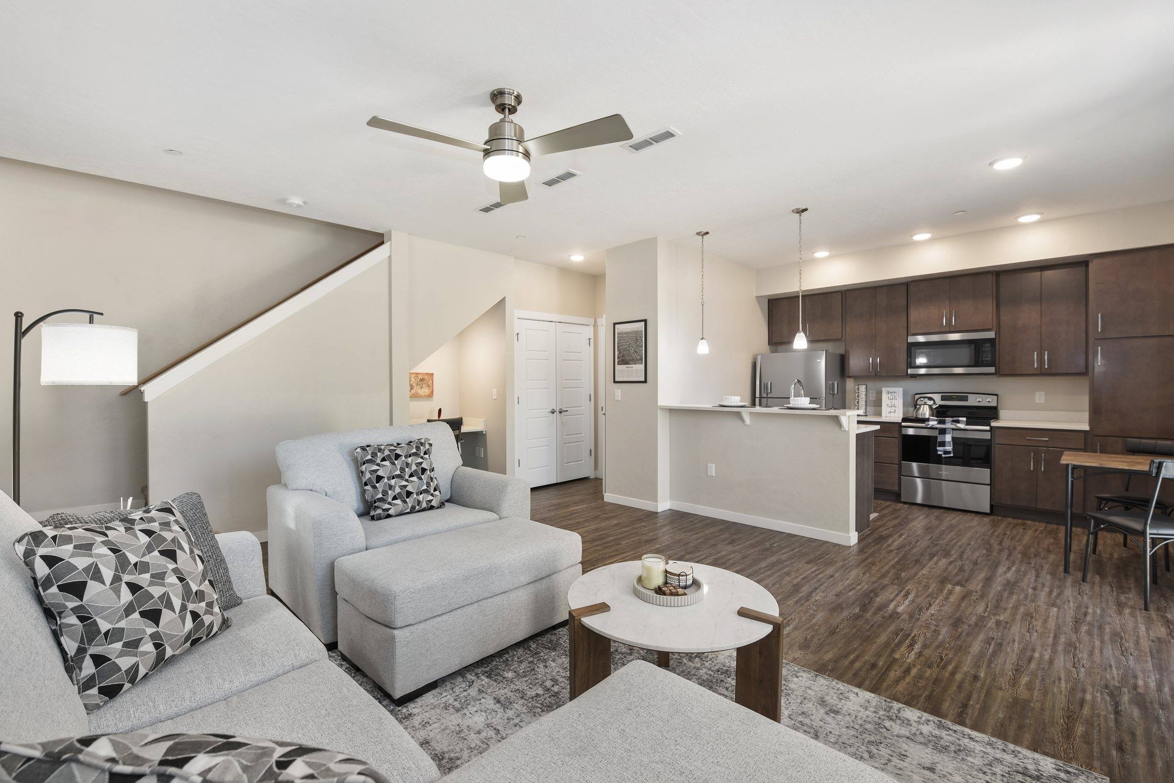 Open great room and kitchen in a furnished model townhome with wood-look floors